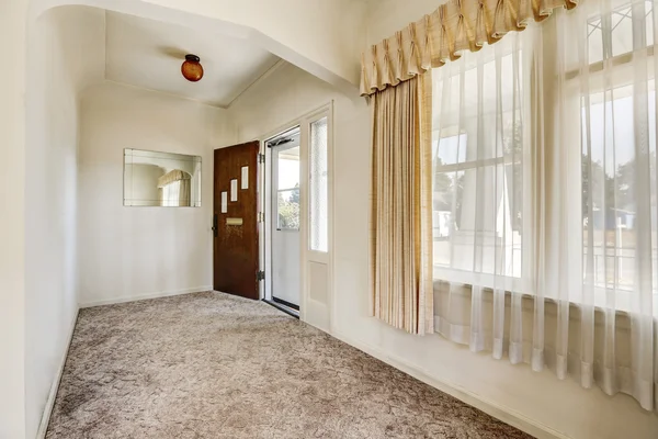 Hallway with view of opened front door and carpet floor