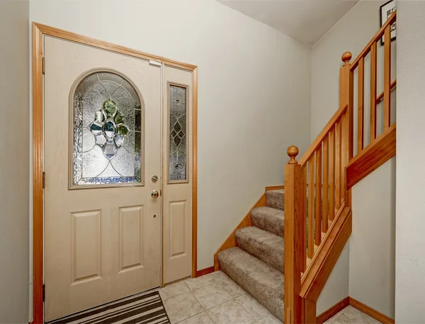 View of wooden staircase and tile floor. House entryway