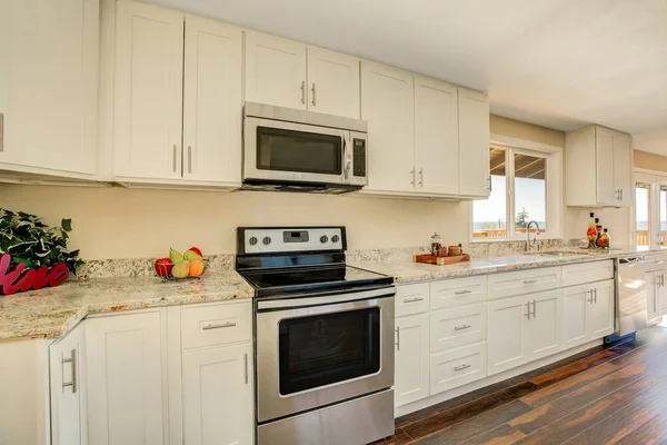 Bright interior of kitchen with white cabinets and granite counters