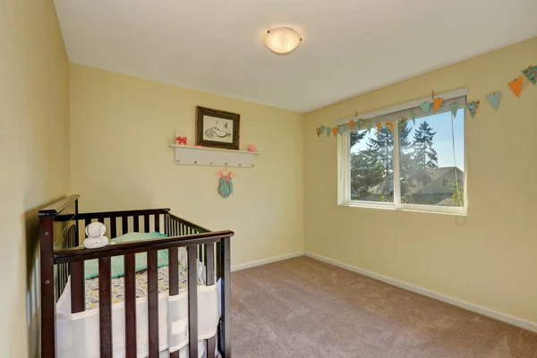 Adorable nursery room. Pastel yellow interior paint and carpet floor