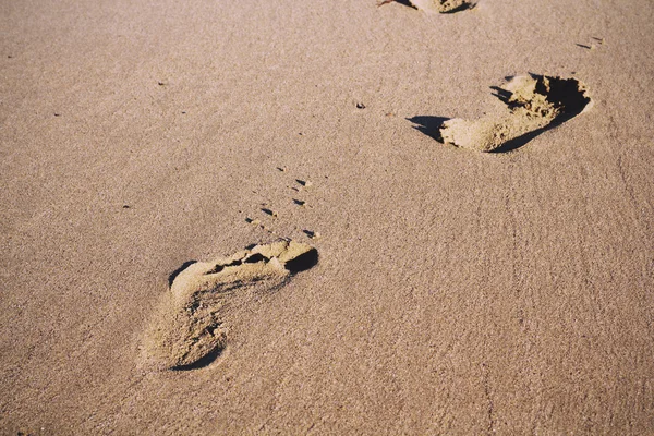 Footprints in the sand on Polzeath beach Vintage Retro Filter.