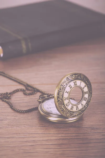 Pocket watch and book against a rustic background Vintage Retro