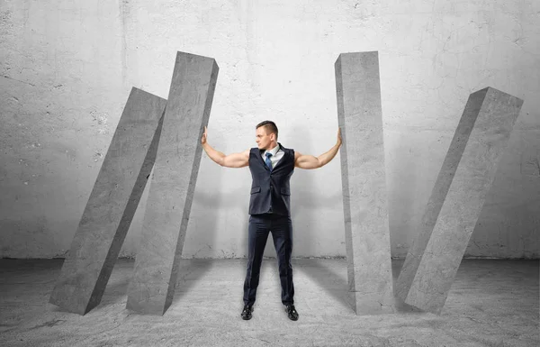Muscular businessman full-height holding concrete four columns falling on him