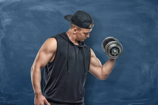 Portrait of young handsome man in black outfit standing and showing his muscled biceps during training