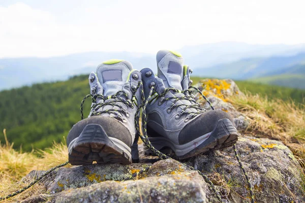 Hiking boots with trekking sticks on the mountain peak