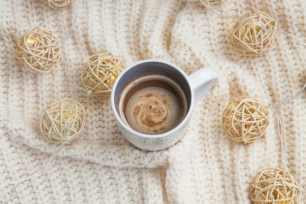 Hot chocolate cup with woolen sweater and lights decoration