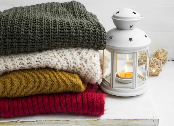 Winter cozy woolen sweaters and candle lantern