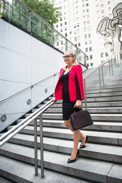 Young adult businesswoman walking on the steps from the office for the meeting and carrying bag