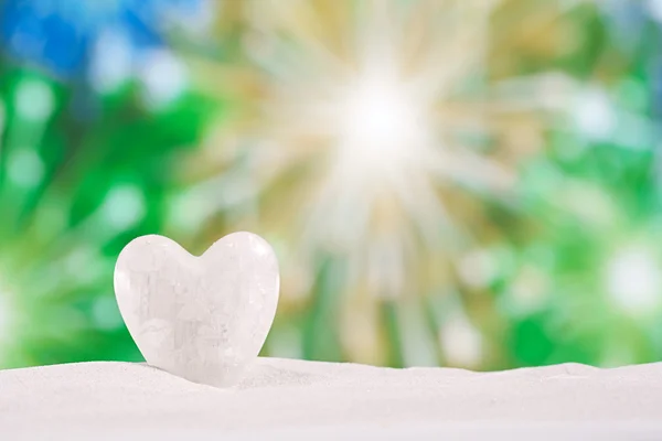 White crystal heart on white sand beach
