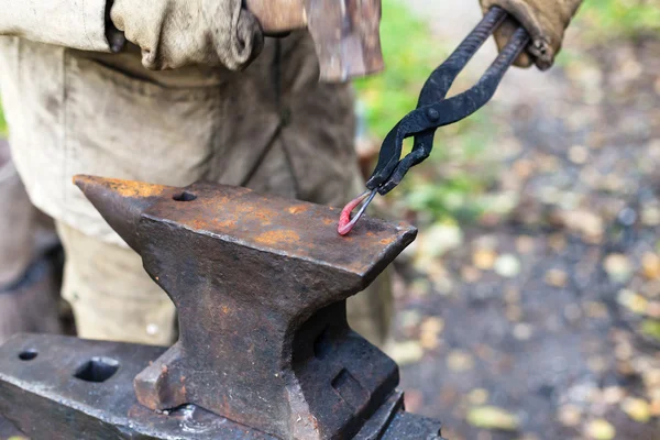 Blacksmith forges a buckle on anvil