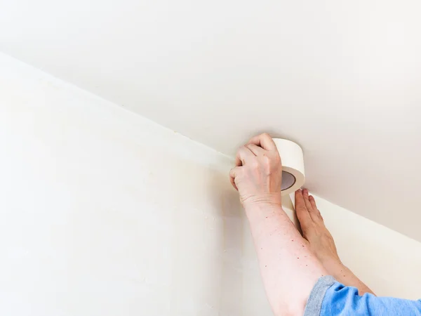 Decorator fixes tape on wall before painting