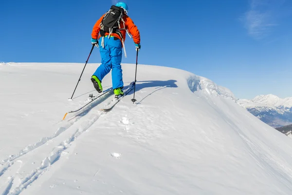 Ski touring man reaching the top at sunny day in Swiss Alps.