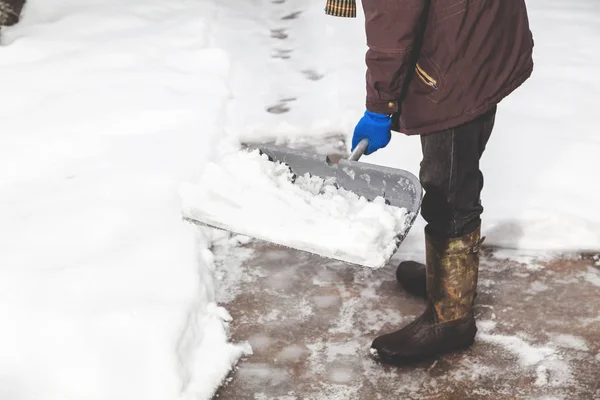 Snow removal. man cleans snow from yard plastic shovel