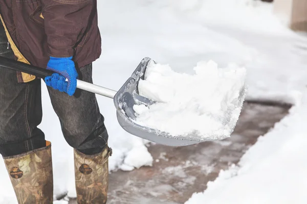 Snow removal. man cleans snow from yard plastic shovel