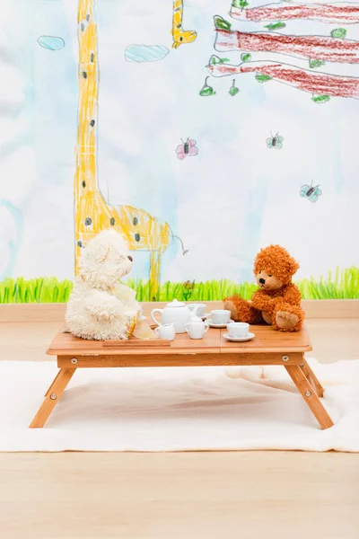 Childs tea set and stuffed toys arranged on small table