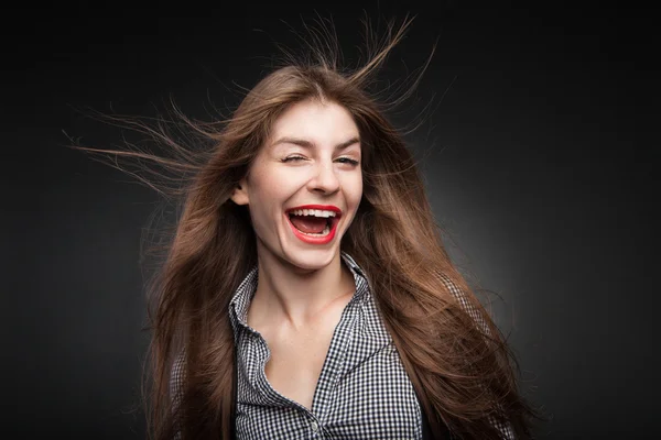 Joyful woman winking with flying hair and wind in her face.