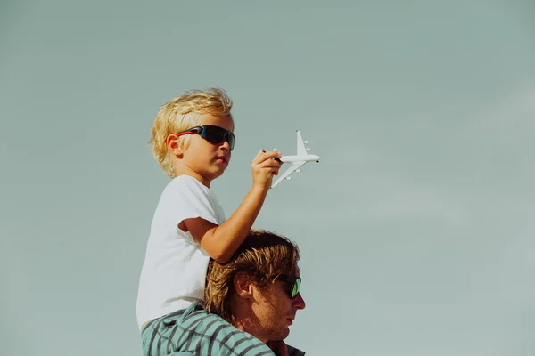 Father and son playing with toy airplane on blue sky