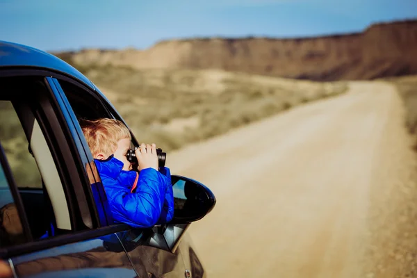Little boy travel by car on road to mountains