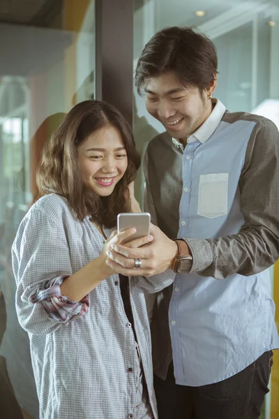 Asian younger man and woman watching on smart phone with happy f