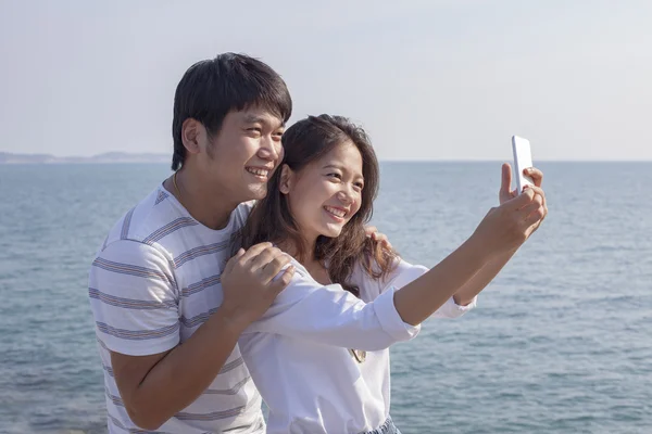 Portrait of younger asian man and woman taking a photograph by s