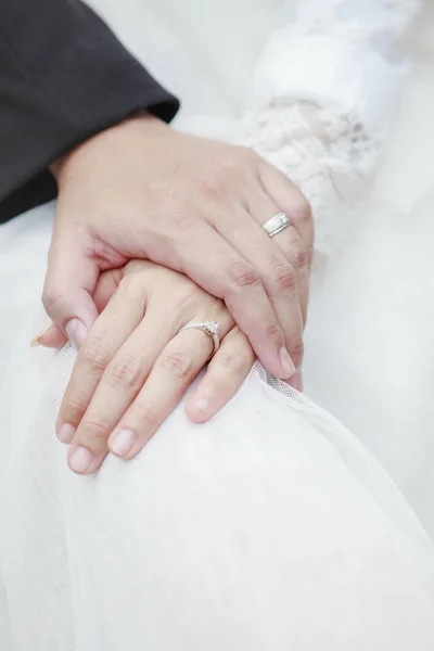 Hand of groom and bride warming holding with wedding daimond rin