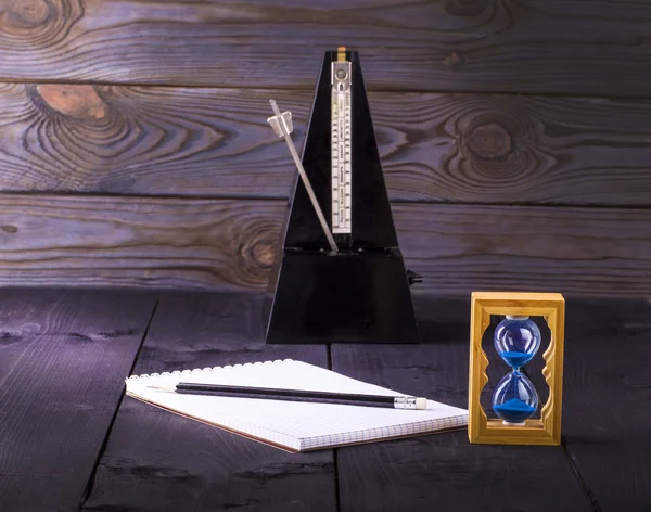 Hourglass, metronome and memo pad with a pencil