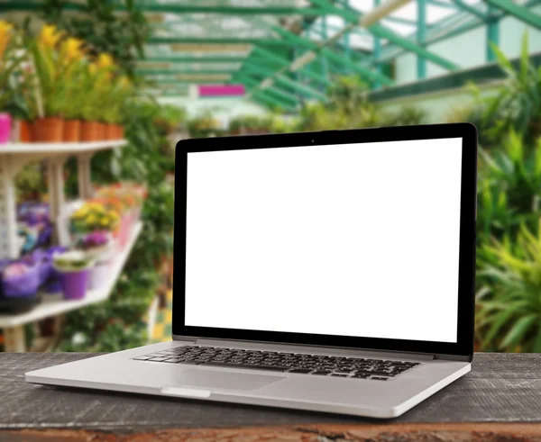 Laptop with blank screen on flower shop background