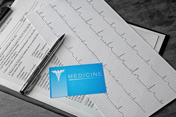 Medical concept. Medical history, business card an ECG chart on grey background