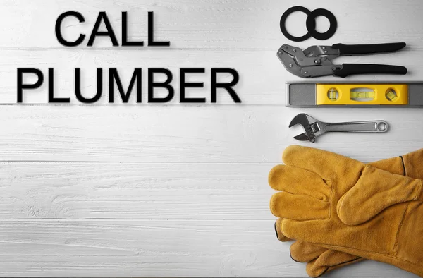 Call Plumber. Plumber tools on white wooden background