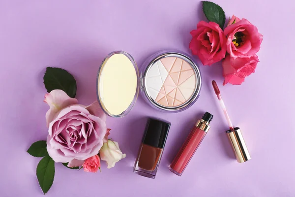 Decorative cosmetics and flowers on purple background