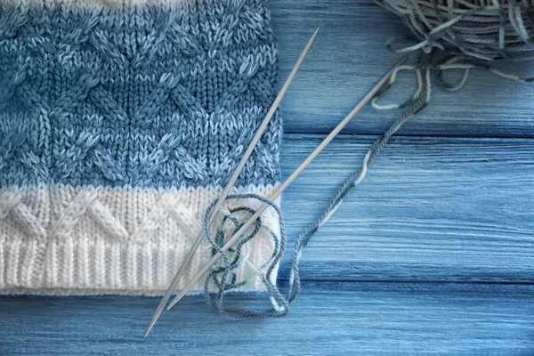 Knitting, needles and yarn on wooden background