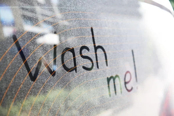 Written text WASH ME on dirty car