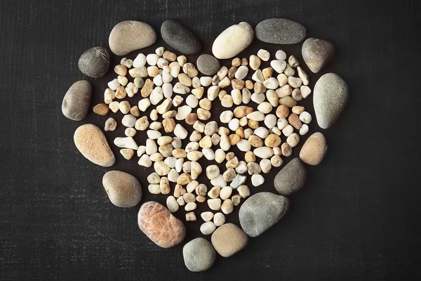 Beautiful heart made of big and small pebbles on dark background