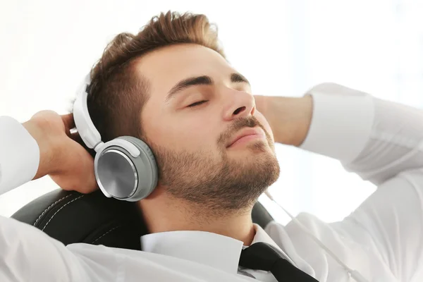 Handsome young man listening to music with headphones at office