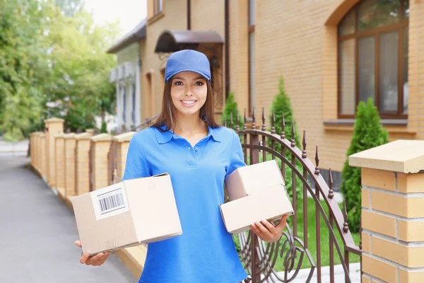 Female courier in uniform delivering parcels outdoor