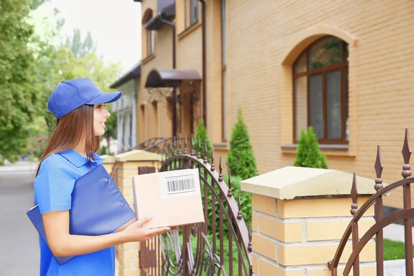Female courier in uniform delivering parcel outdoor