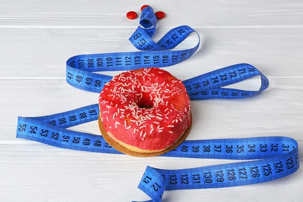 Delicious doughnut and measuring tape