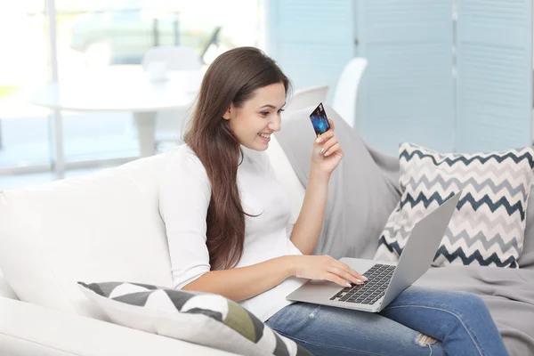 Young happy woman with laptop and credit card making online shopping