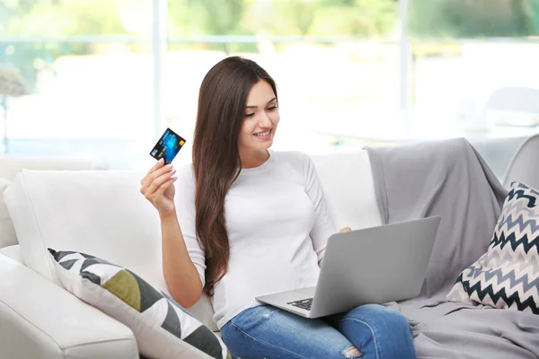 Young happy woman with laptop and credit card making online shopping
