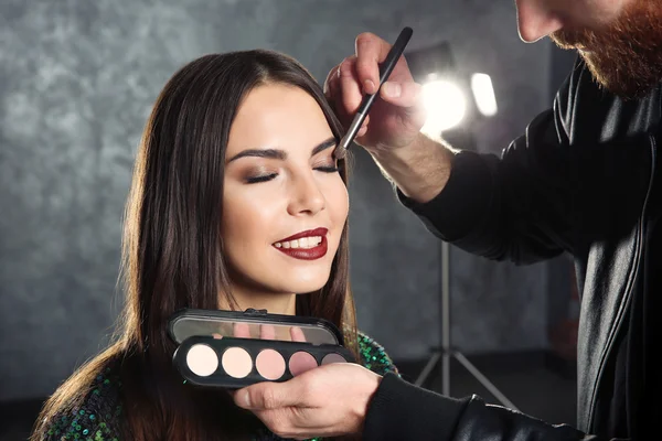 Professional makeup artist working with beautiful young woman