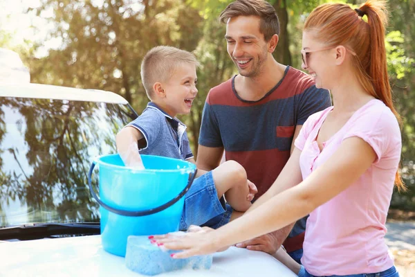 Happy family washing car on street