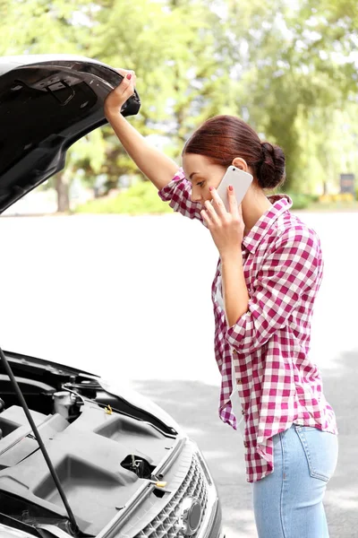 Woman with cellphone and broken car