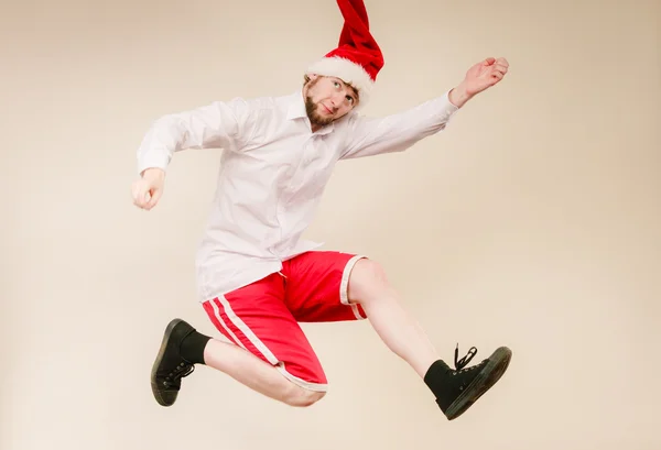 Active man in santa hat dancing and jumping.