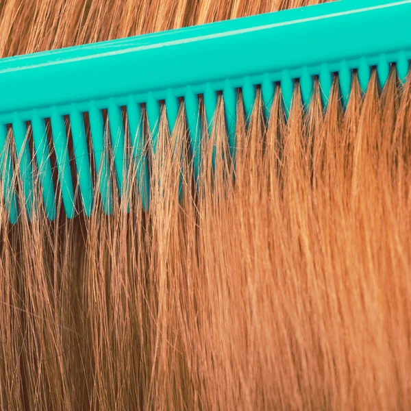 Close up of green comb in red hair.