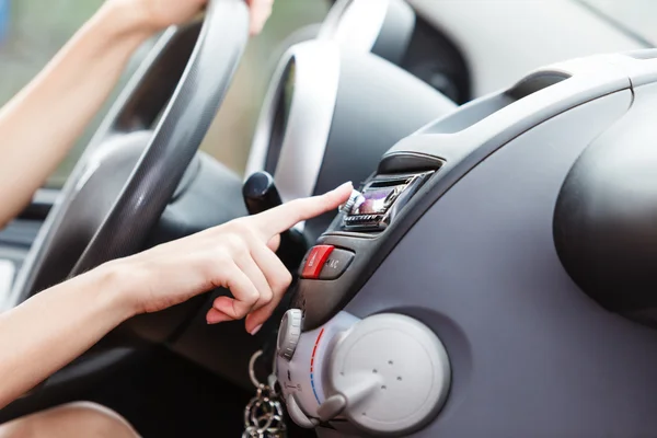 Woman changing radio station in her car