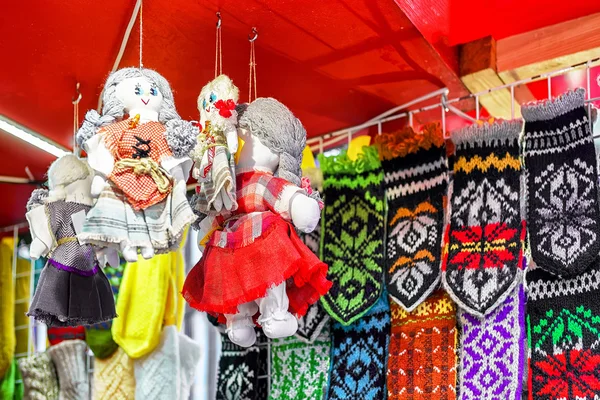 Textile dolls hanging near woolen mittens at Riga Christmas market