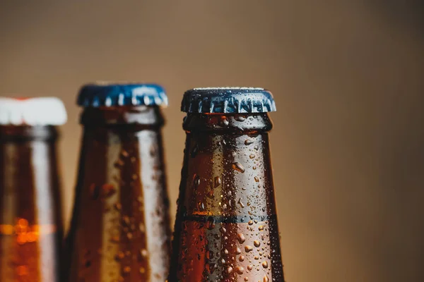 Close-up of fresh cold beer ale bottles with drops and focus on stopper