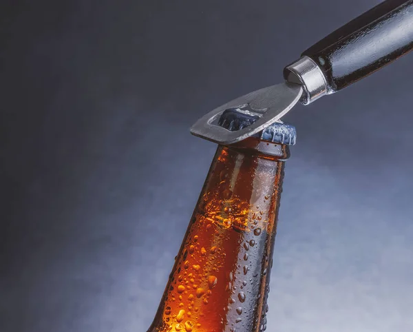 Fresh cold beer ale bottle with drops and stopper open with bottle opener