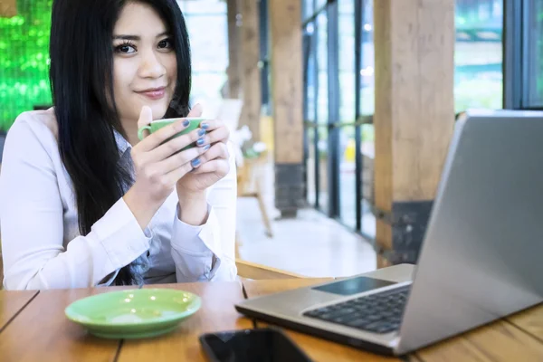 Woman enjoying coffee with laptop