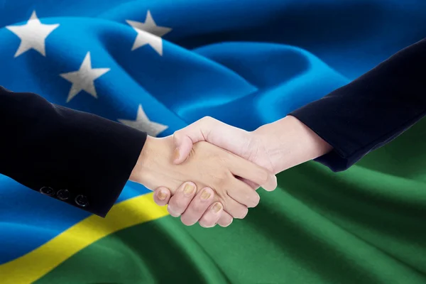Cooperation handshake with flag of Solomon Islands